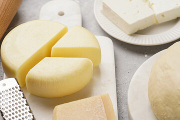 Various cheese types on marble and porcelain plates and fresh dough - ingredients for traditional georgian open pie khachapuri