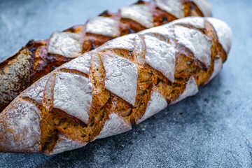 Homemade whole grain bread with notches, french baguette  with sourdough on a dark background, copy space. Craft bread background banner