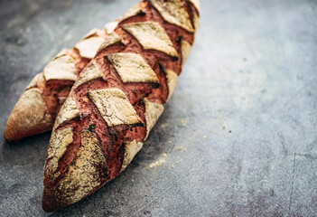 Homemade whole grain bread with notches, french baguette  with sourdough on a dark background, copy...