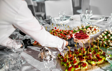 woman hands of a waiter prepare food for a buffet table in a restaurant