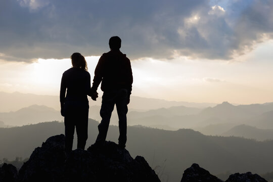 Silhouette loving couple holding hands looking natural mountains sunset background. love and valentines concept.
