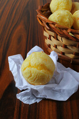 Brazilian snack with cheese buns basket in the background on the wooden table. Seletive focus.
