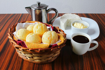 Brazilian cheese bread. Seletive focus. Basket of cheese bread with coffee, teapot, butter and white cheese.