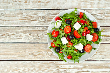 Greek salad in a white bowl. Fresh vegetable salad on a white background. Food on a shabby table. Bowl on an old wooden board. Copy space and free space for text near food.