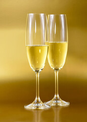 Two glasses of champagne on a golden background stock images. Sparkling wine isolated on a gold shiny background vertical stock photo. Celebration drink images