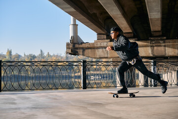Obraz premium Skater rides on skateboard at empty concrete embankment on the urban background