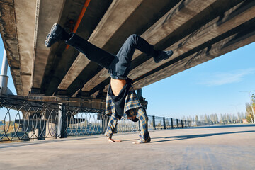 Young man break dancer dancing on urban background performing acrobatic stunts