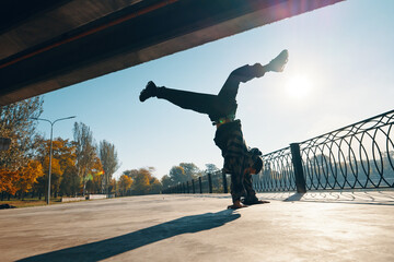 Young man break dancer dancing on urban background performing acrobatic stunts