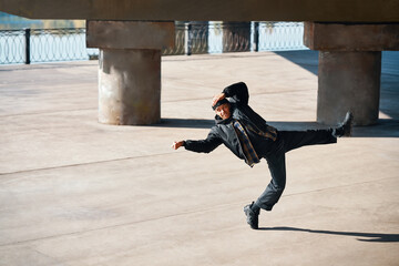 Stylish man dancing hip-hop on the street urban background