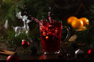 red tea in a glass splashes up due to the fact that a strainer with tea leaves falls into it.