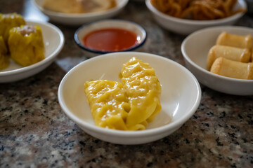 Steamed Asian dumplings, made from minced pork mixed with shrimp and pepper, famous breakfast dim sum at Trang, Thailand with background of varieties of dim sum.