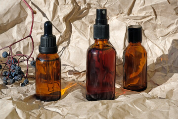 Glass brown bottles on a background of crumpled craft paper. Cosmetic bottles close up. Hyaluronic acid oil mockup. serum cosmetic. Transparent liquid product in glass bottle with dropper.
