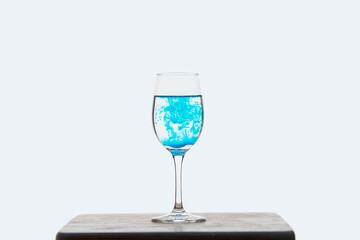 Blue ink drips into the glass with water and creates beautiful colored lines.
