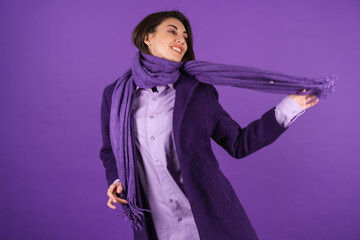 Young woman in a woolen coat and scarf on a purple background, cozy and warm, autumn-winter spring...