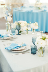Wedding tables for guests with a blue tablecloth. Decorated with premium glasses and flowers
