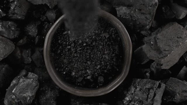 Super Slow Motion Shot of Pouring Crushing Coal into Black Bowl at 1000 fps.