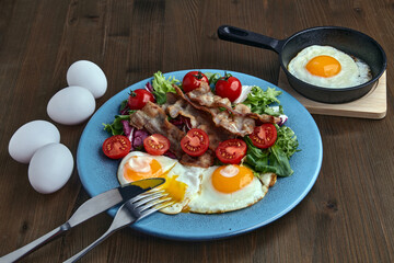 Fried eggs with bacon, lettuce and cherry tomatoes