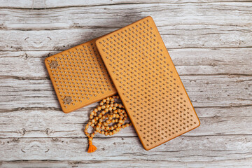 Tibetan Buddhist rosary, called mala or japamala. Brown Sadhu wooden boards with nails for yoga and spiritual practices on the grey background. The concept of meditation, standing on nails, therapy.