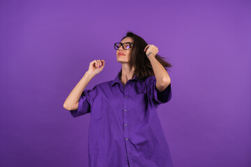 A young woman in a shirt with a short sleeve on a purple background, with makeup and stylish...