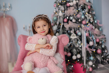 Obraz na płótnie Canvas Smiling child girl under Christmas tree with decorations in room.