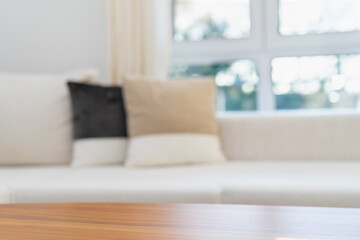 Empty wooden tabletop with white sofa in the modern living room on which product can be placed