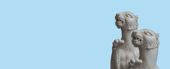 Banner with ancient marble statues of two scary panthers of Roman Renaissance Era at solid blue sky background with copy space.