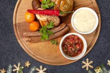Christmas grilled sausages with spices on a stone background with Christmas trees and Christmas decorations, gifts
