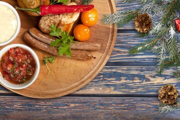 Obraz na płótnie Canvas Christmas grilled sausages with spices on a stone background with Christmas trees and Christmas decorations, gifts