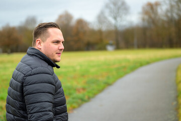 Young man turning back as he walks along a rural road