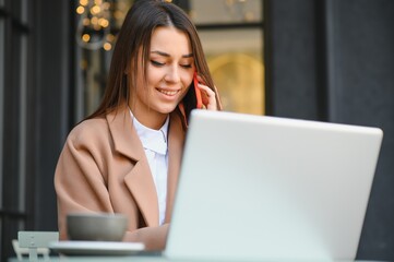 Photo portrait of gorgeous attractive woman working on laptop typing sitting in cafe drinking coffee