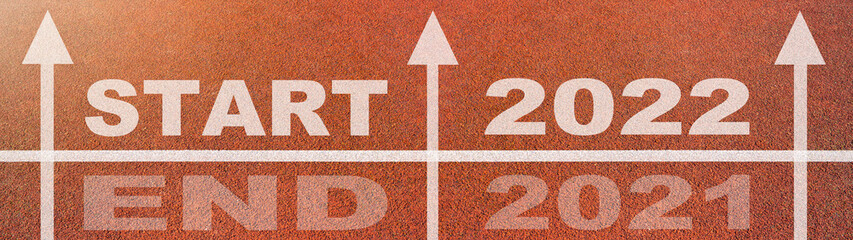 New year 2022 or start straight concept background banner panorama. Word START 2022, END 2021 written on the orange running track on sports field with arrow, top view