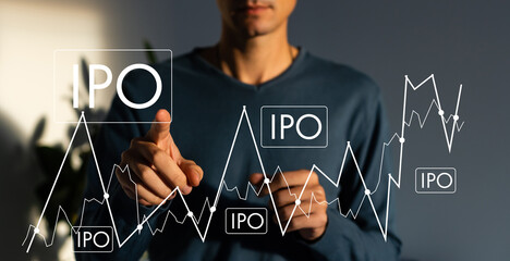 IPO - Initial Public Offering concept with hand pressing a button on blurred abstract background.