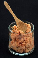 Tartare de saumon dans une verrine avec une cuillère en bois en gros plan sur fond noir