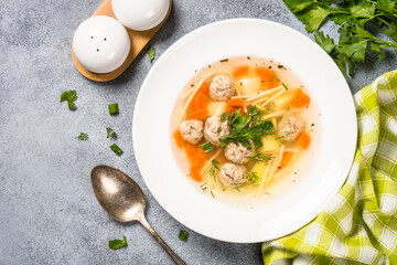 Meatballs soup with vegetables. Traditional Ukrainian dish. Top view on light stone table.