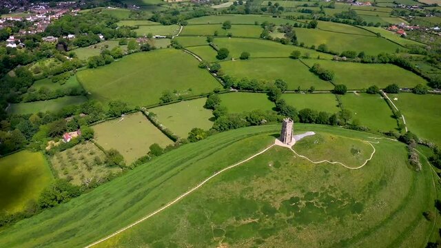 Glastonbury tor filmed from drone on sunny day, footage was taken from dji mavic pro 2 drone, iconic monument in the middle of the countryside