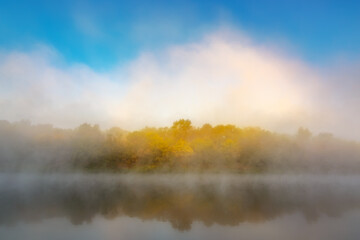 Fototapeta na wymiar Autumn fog over the river and forest with yellow leaves.