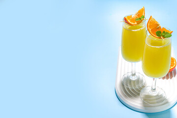 Classic summer mimosas cocktail, with orange juice, on  light blue background. Summer bar menu concept copy space