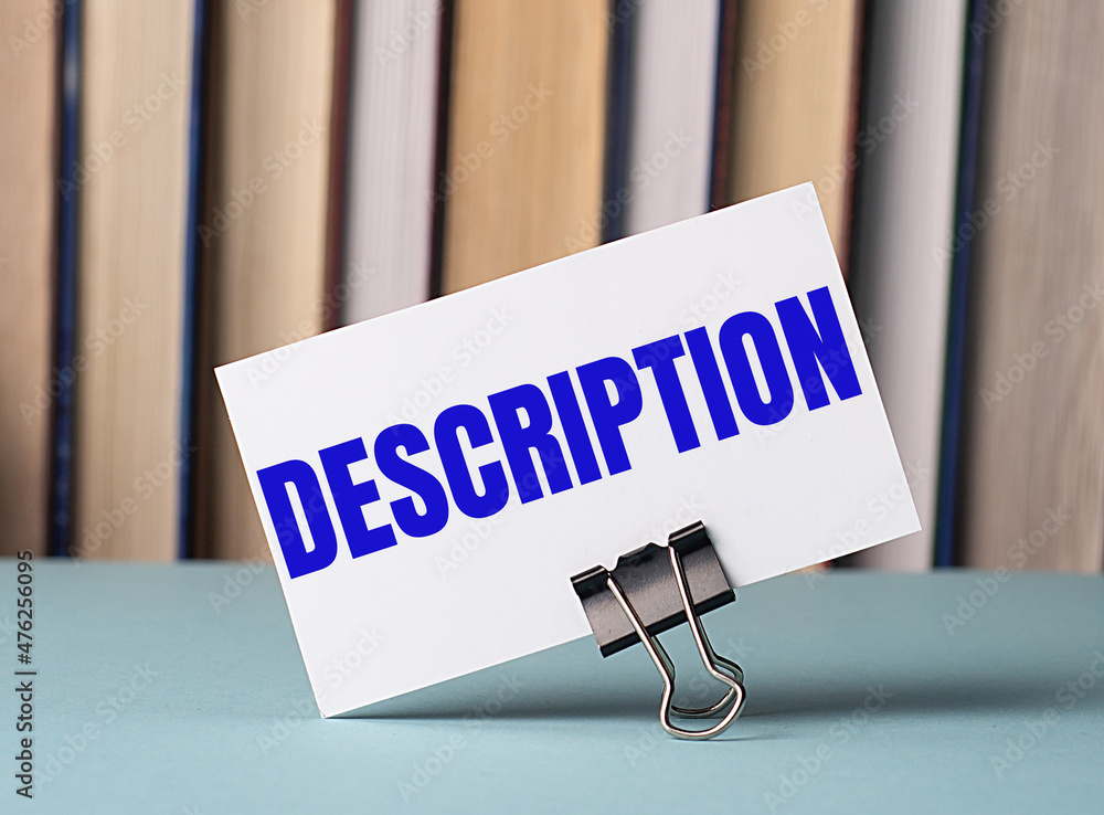 Poster a white card with the text description stands on a clip for papers on the table against the backgrou