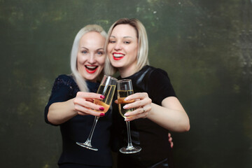 Nice girls hugging with joyful wide smile  with champagne in a glasses on the party. focus on glasses