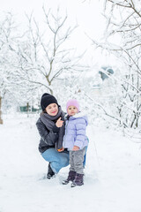 Fototapeta na wymiar Happy mom and child spend time together and play. Walk in the snowy park.