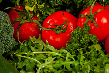 Cabbage, peppers, tomatoes, cucumbers, lettuce, cherry tomatoes, broccoli, arugula on a black background. variety of vegetables on a pile on a wooden table.