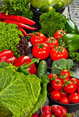 Cabbage, peppers, tomatoes, cucumbers, lettuce, cherry tomatoes, broccoli, arugula on a black background. variety of vegetables on a pile on a wooden table.