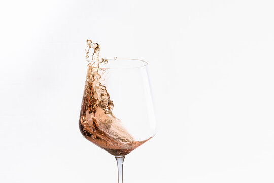 Glass of splashing alcohol on a light background