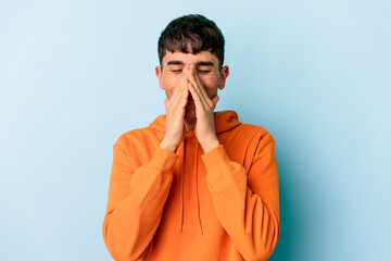 Young mixed race man isolated on blue background holding hands in pray near mouth, feels confident.