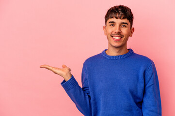 Young mixed race man isolated on pink background showing a copy space on a palm and holding another hand on waist.