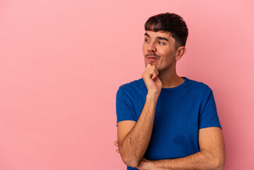 Young mixed race man isolated on pink background relaxed thinking about something looking at a copy space.