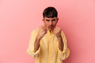 Young mixed race man isolated on pink background showing fist to camera, aggressive facial...