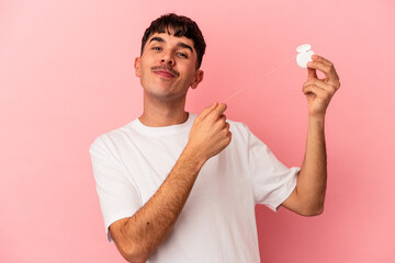 Young mixed race man holding a floss isolated on pink background