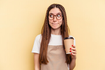 Restaurant waiter woman holding a take away coffee isolated on yellow background confused, feels...