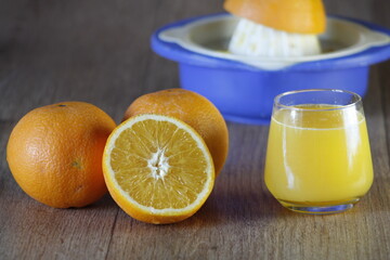 Blue squeezer and a glass of homemade orange juice and slice on wooden texture background. Close up.